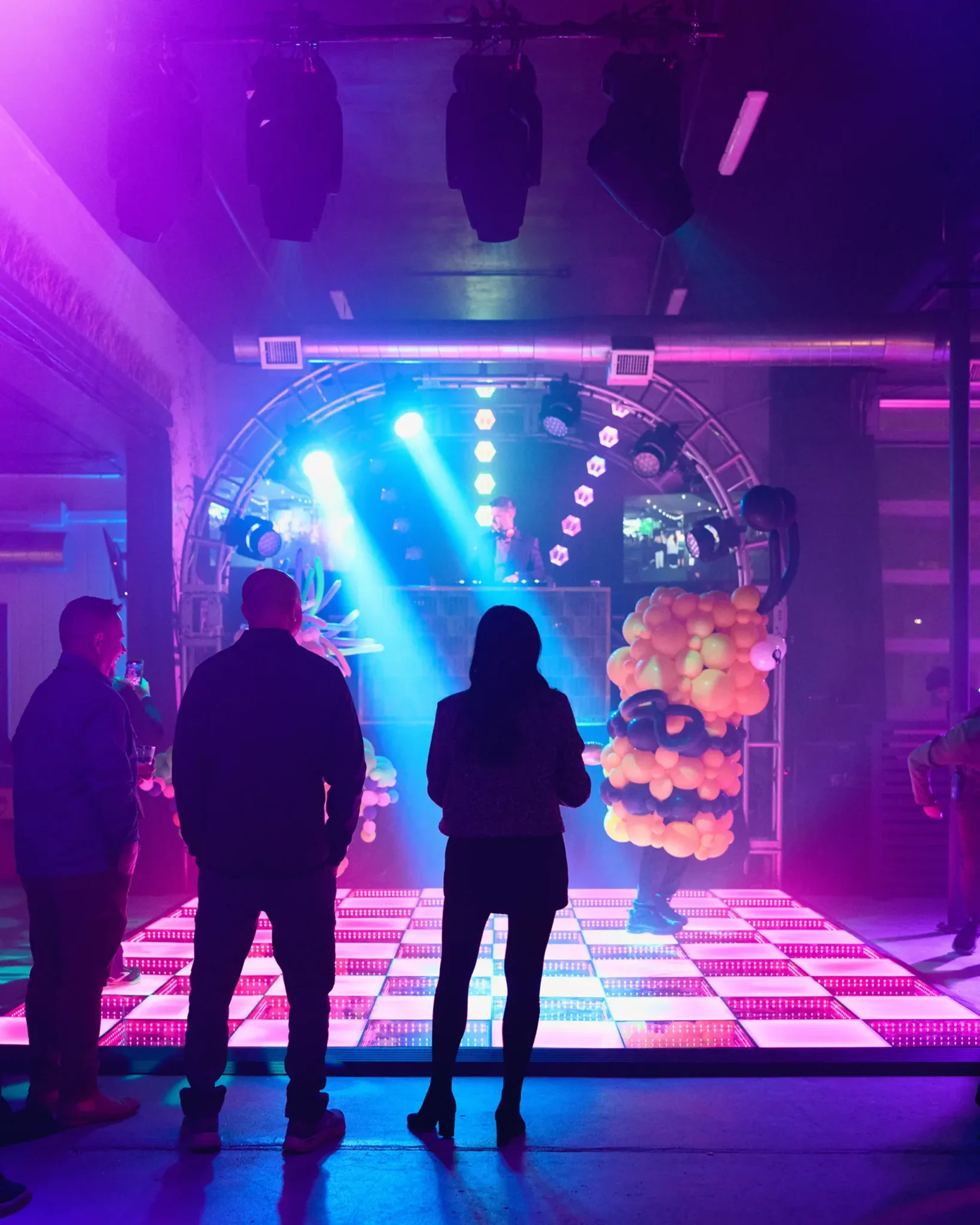 Guests watching a balloon performer on an LED dance floor under purple stage lighting at the PRI industry event