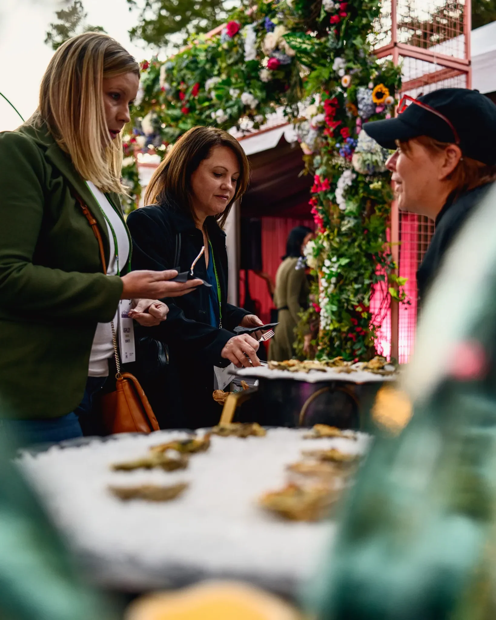 Guests at an oyster station beside a floral installation at the PRI industry event at Citri San Marco