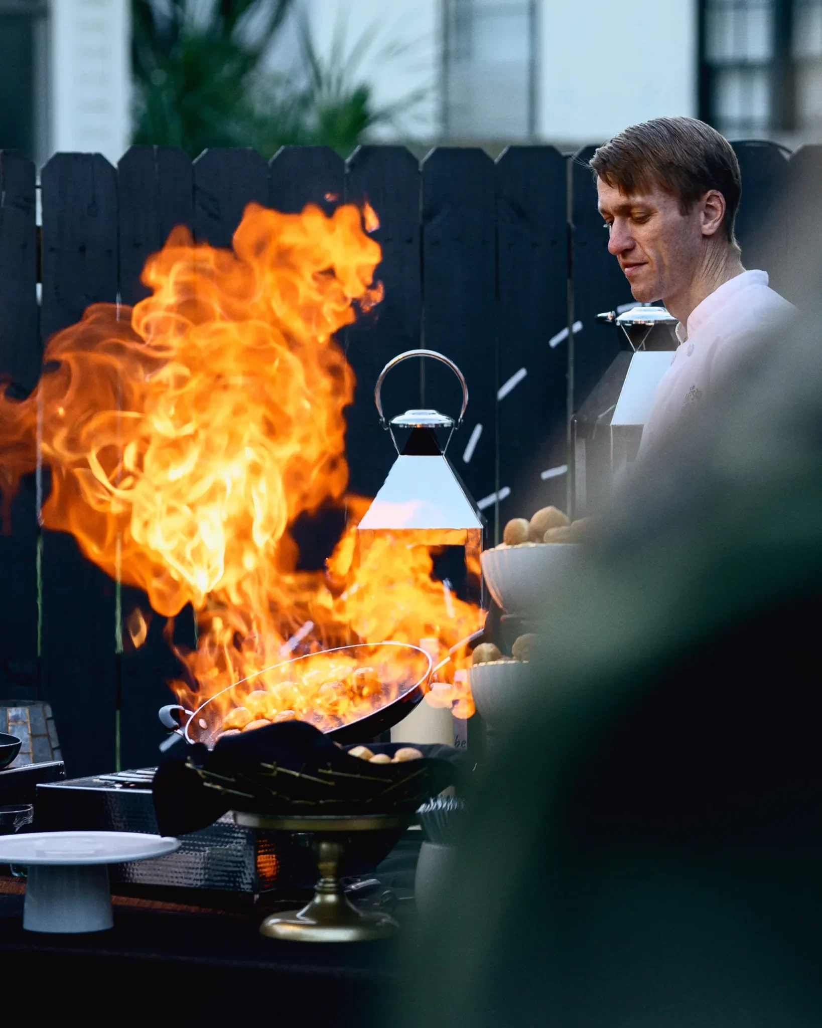 Chef in a white coat cooking over a high flame at an outdoor station during the PRI industry event