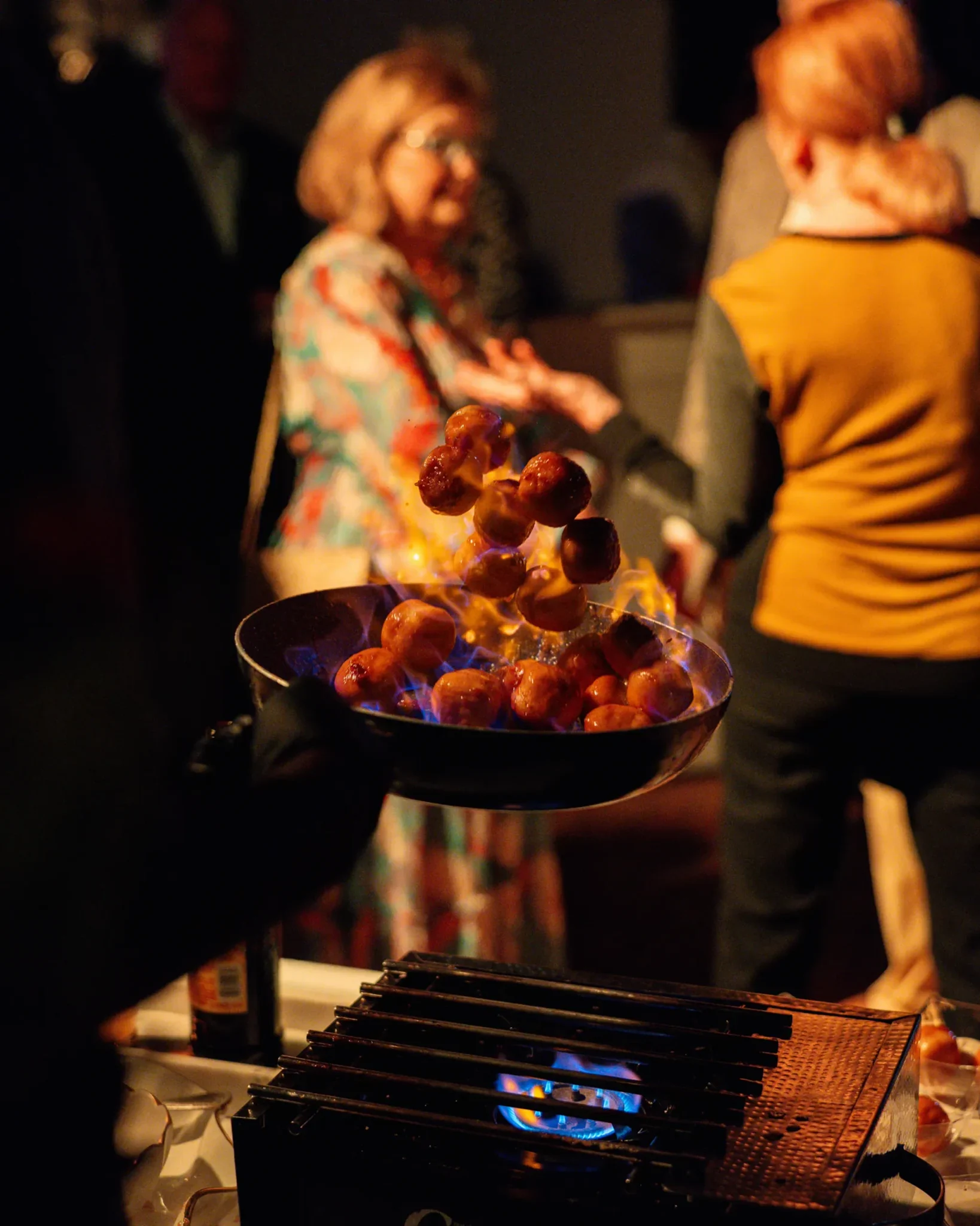 Chef tossing flaming appetizers in a pan at the San Marco Centennial Soirée